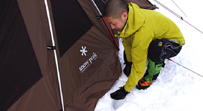 雪中キャンプでスカート処理をする男性