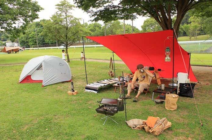 赤いタープでソロキャンプを楽しむ男性