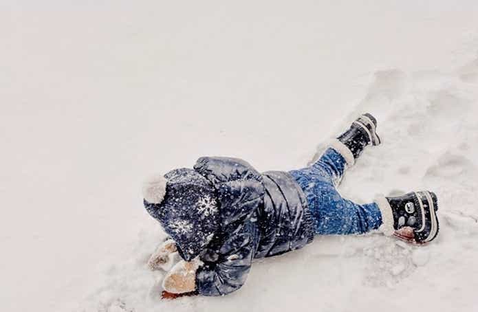 ソレルのブーツを履いて雪の中で遊ぶ子供