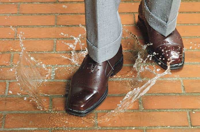 防水スプレーをかけた革靴で水たまりを歩く男性