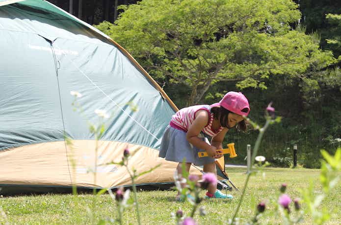キャンプ場でテントのペグダウンをする女の子