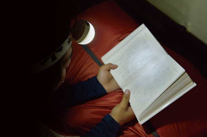 スノーピークのヘッドランプ、テントの中、読書する人