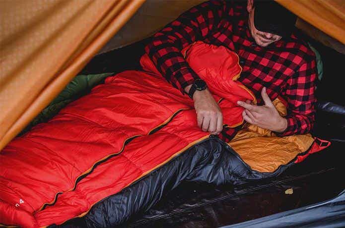 シュラフでテント内で寝る人