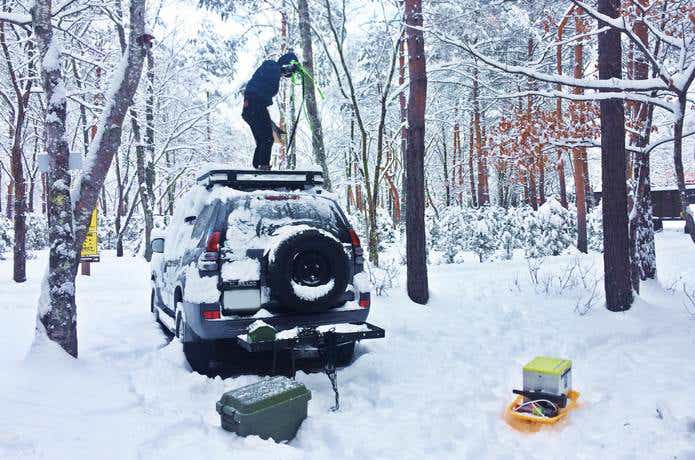 雪キャンプ　車の雪かきをする人