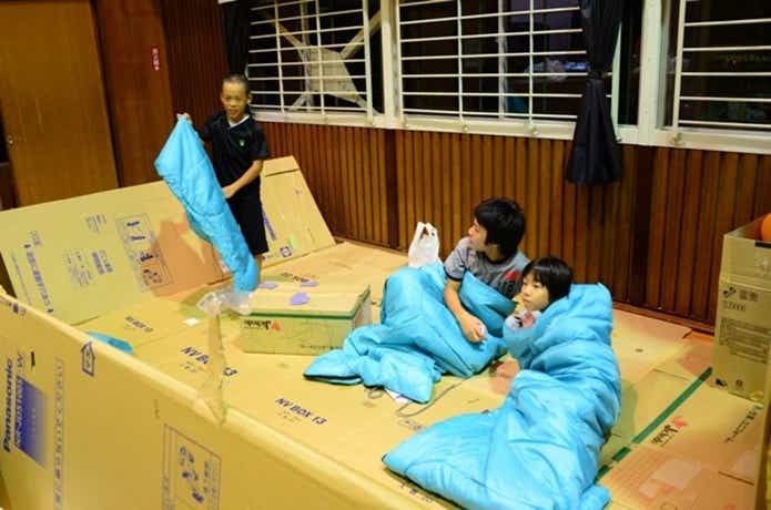 避難所で寝袋で寝る子供達