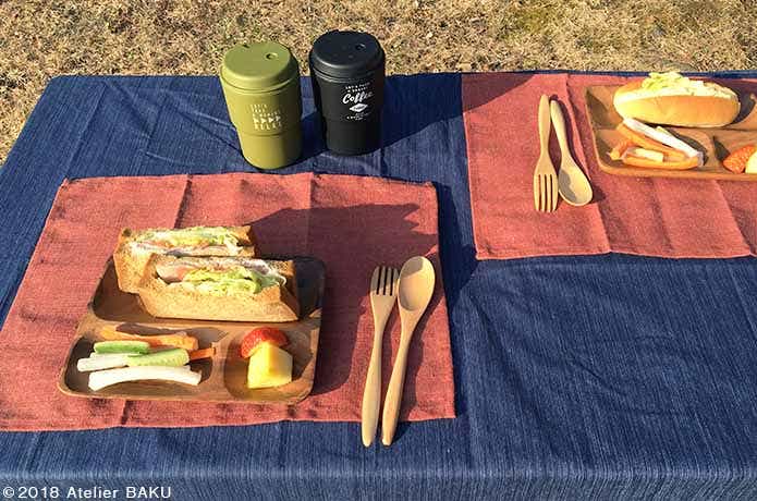 テーブルの上のタンブラー、木製トレー、カトラリー、サンドイッチ