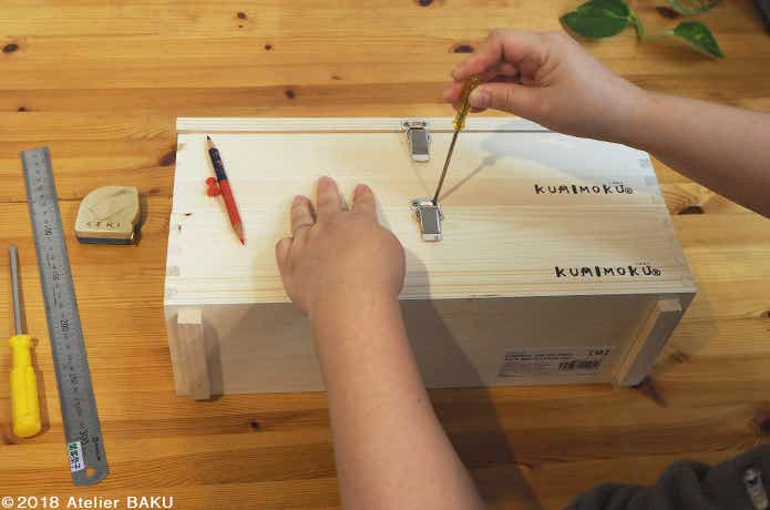 木製BOXに接続金具を取り付ける手、ドライバー、色鉛筆、画鋲