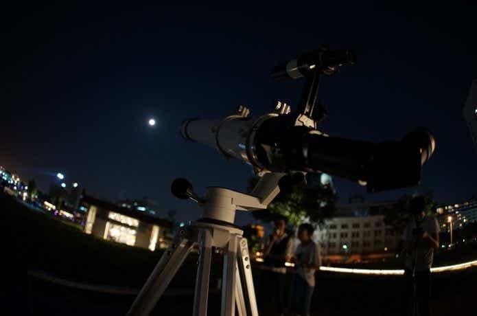 天体望遠鏡で月を観察する人
