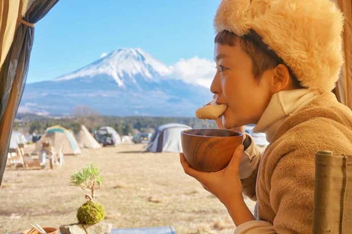 富士山の見えるキャンプ場で食事をする女性