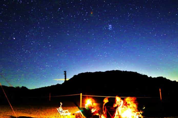 キャンプファイヤーと満天の星空の山牧場キャンプ場