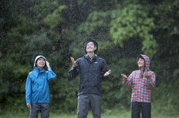 レインコートを着て雨を受ける男性と子供