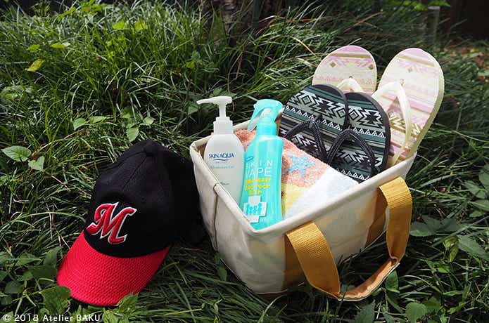 ビーチサンダル、タオル、虫除け、日焼け止めの入った折りたたみバッグ、帽子