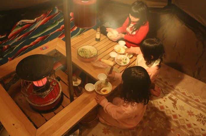 秋冬キャンプ　ストーブを囲炉裏で囲む　子供達の食事風景