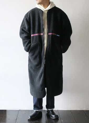 冬キャンの防寒ウェア　ロング丈のモコモコ服を着る男性