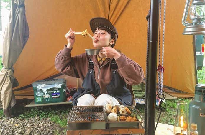 キャンプでお餅を焼いて食べる女性
