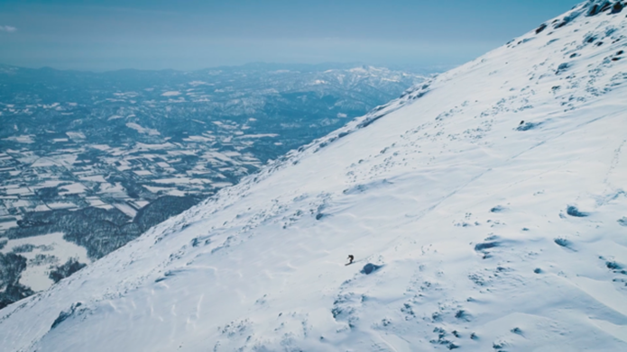 ドローンで撮影した雪山を滑るスキーヤー