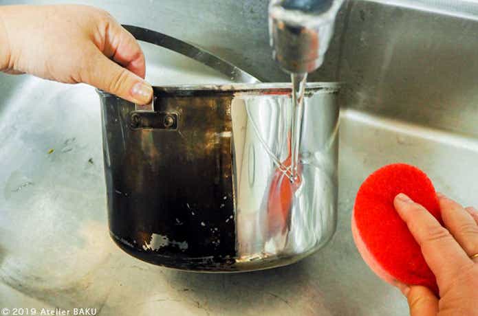 鍋をスポンジでこすり洗い