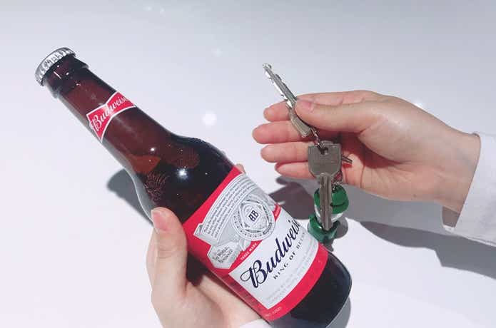 左手に瓶ビール、右手に鍵を持っているシーン