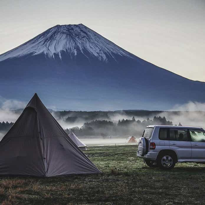 キャンプ場に設営したテントと車と雪冠の山