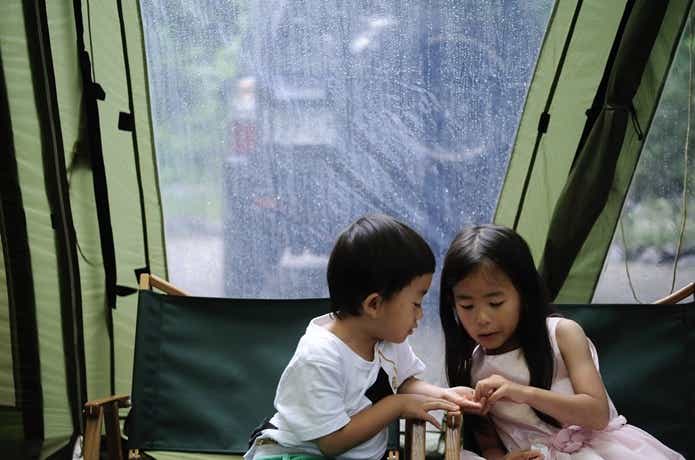 雨の中テントで遊ぶ子供