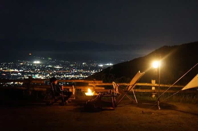 夜景の見えるキャンプ場でキャンプを楽しむ男性