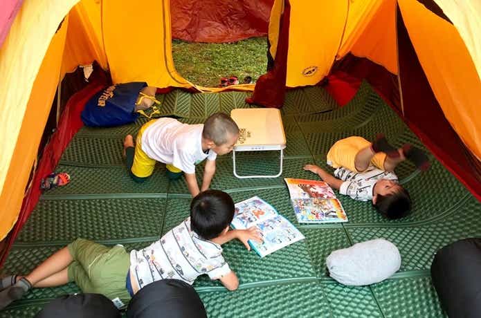 テント内で本を読む子供たち