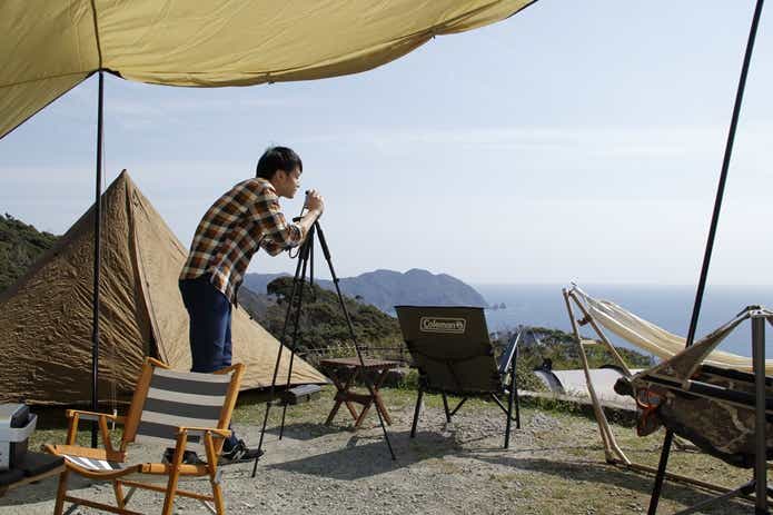 絶景キャンプ場からの景色を写真に撮る男性