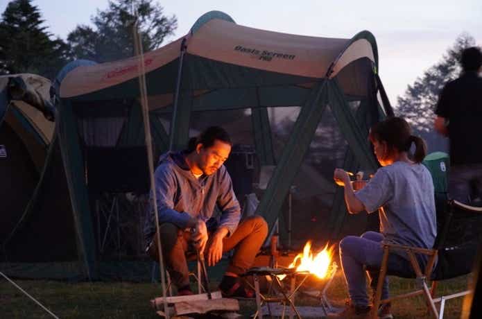 キャンプで焚き火を楽しむ男女