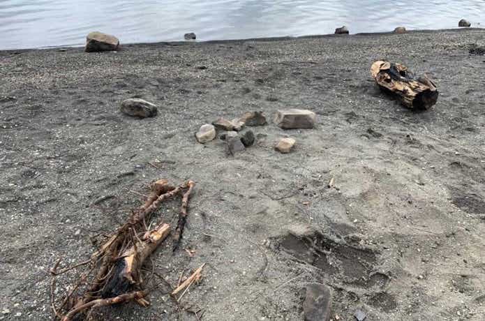 燃え残った薪が捨てられた砂浜