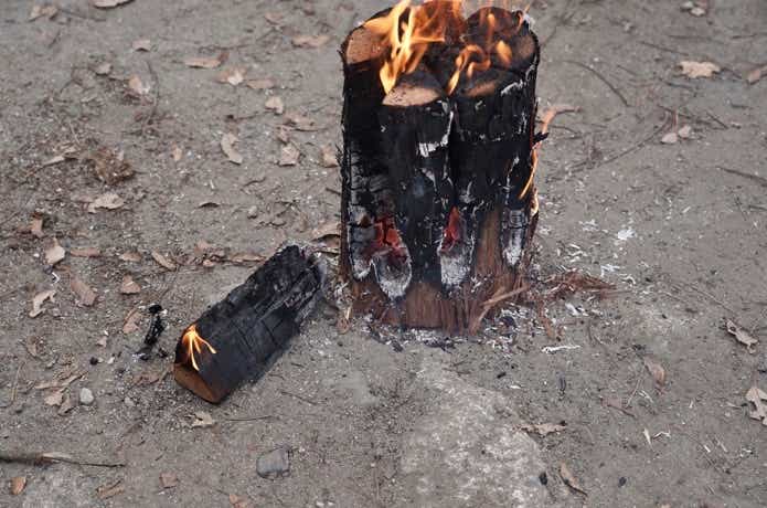 地面に火のついた薪が落ちたスウェーデントーチ