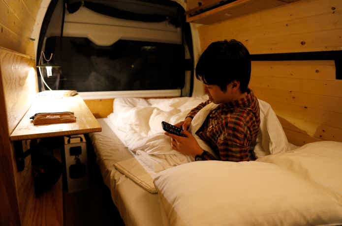 バンライフカー 車内のベッドで横になる濱松