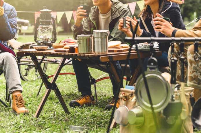 キャンプでテーブルを囲む男女グループ