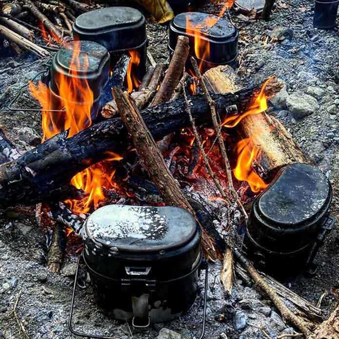 ドイツ連邦軍式飯盒5個を焚き火にくべて同時炊飯している画像