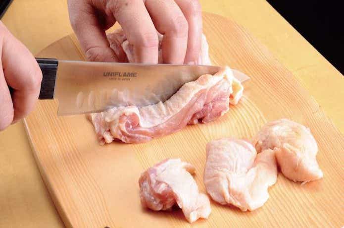ユニフレーム「ギザ刃 牛刀」で鶏肉を切っている