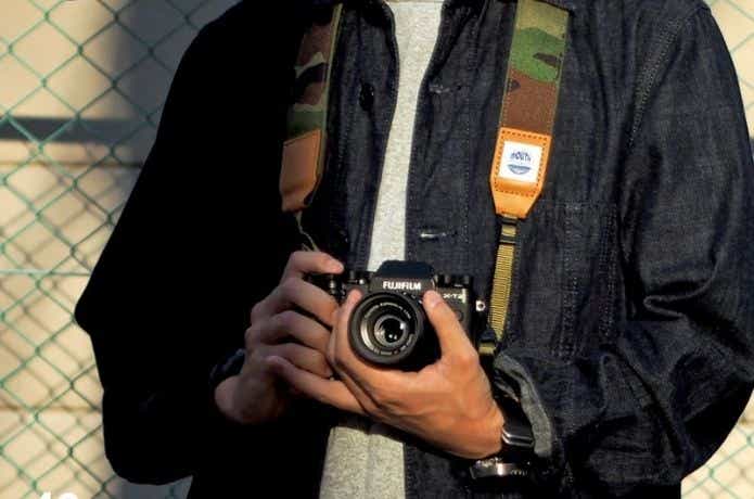 カモ柄のストラップでカメラを持つ男性