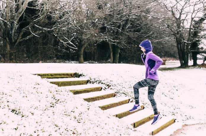 雪の積もる階段を進む女性ランナー