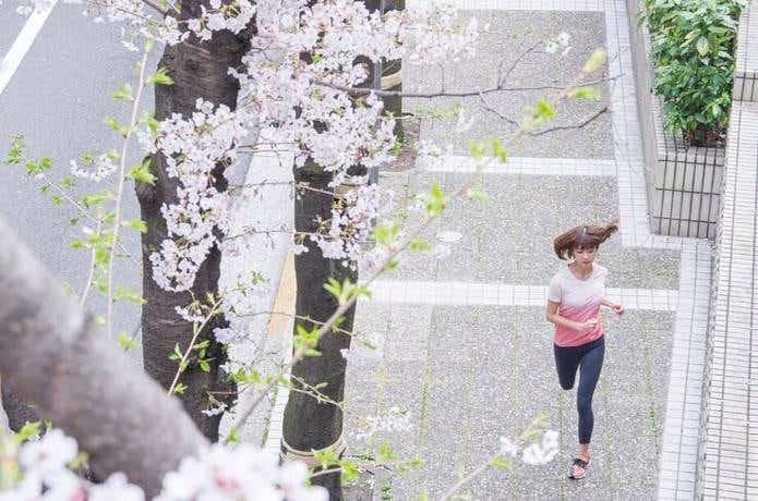 桜の下を走る女性