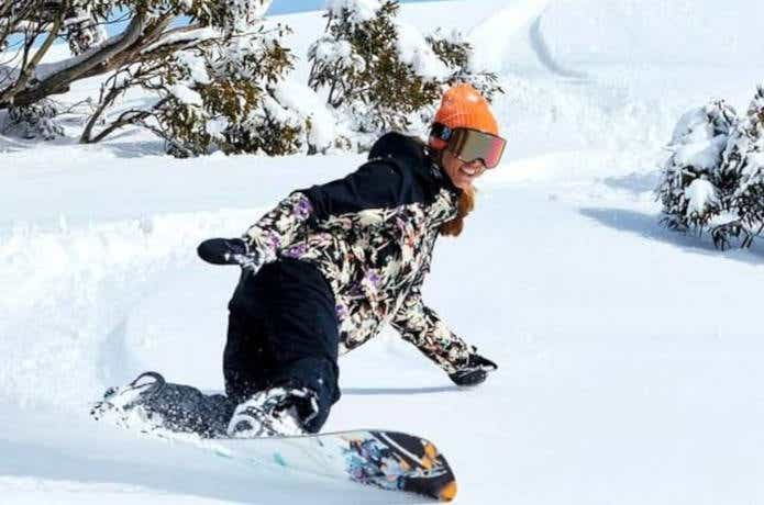 パウダーをスノーボードで滑走する女性