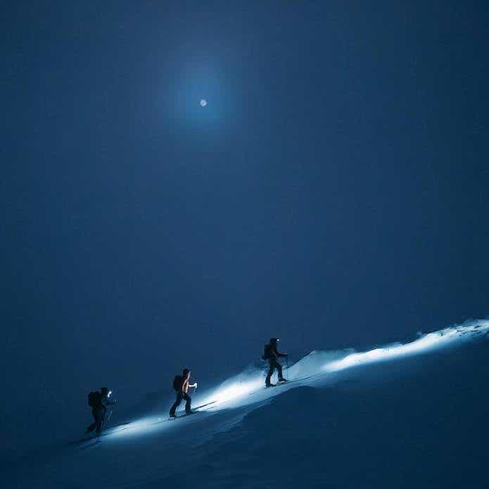 3人の登山家が雪山を登っている