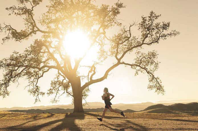 木のそばを走る女性ランナー