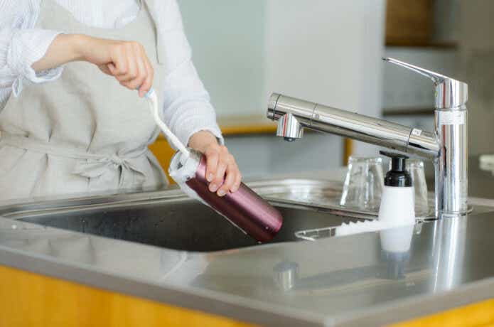 ブラシで水筒を洗っている女性