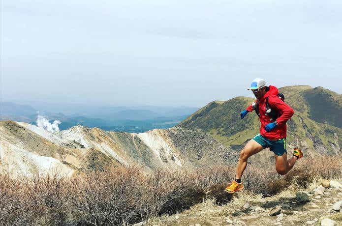 ランニング用バックパックを背負って山際を走る男性