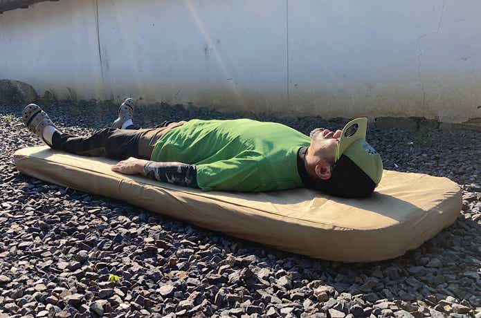 砂利に敷いたDOD「ソトネノキワミS」の上に寝る人
