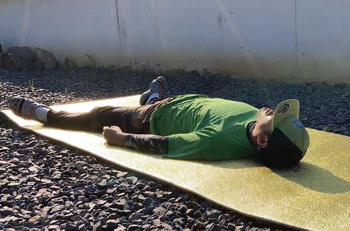 砂利に敷かれた銀マットの上で寝る人