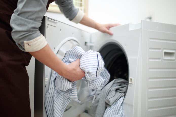 ドラム式洗濯機から洗濯物を取り出す女性