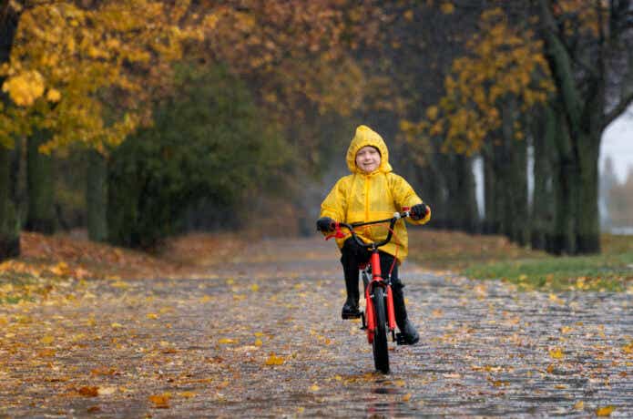 レインコートを着てジュニア向け自転車に乗る子供