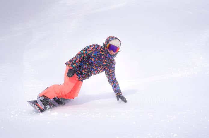 雪面を曲がりながら滑るスノーボーダー