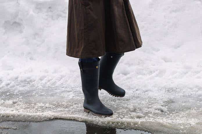 防寒長靴で雪の水辺を歩く