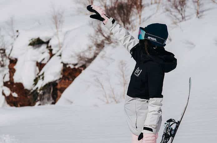 空に手を伸ばす女性スノーボーダー