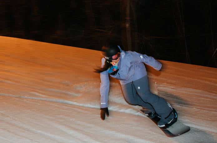 夜に滑る女性スノーボーダー
